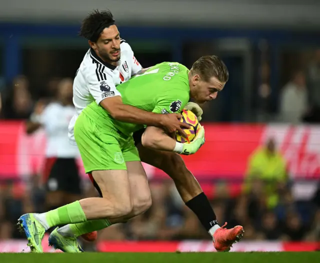 Pickford tries to hold onto the ball as Jimenez tries to grab it off him