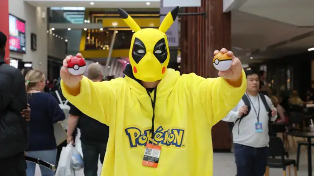 A Pikachu-Deadpool crossover cosplayer holding two Poké Balls in hand