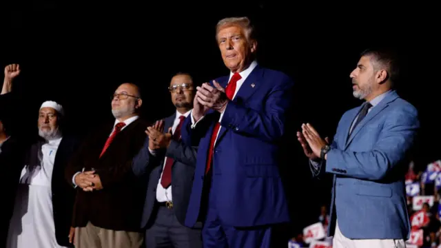 Republican presidential nominee, former US President Donald Trump, stands with supporters on stage during a campaign rally at Suburban Collection Showplace on October 26, 2024 in Novi, Michigan.