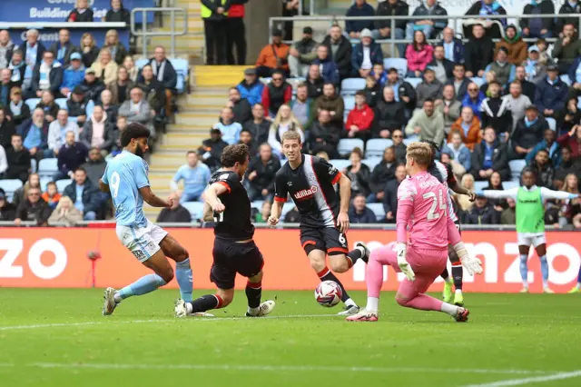 Luton Town goalkeeper Thomas Kaminski (right) saves a shot on goal from Coventry City's Ellis Simms (left)