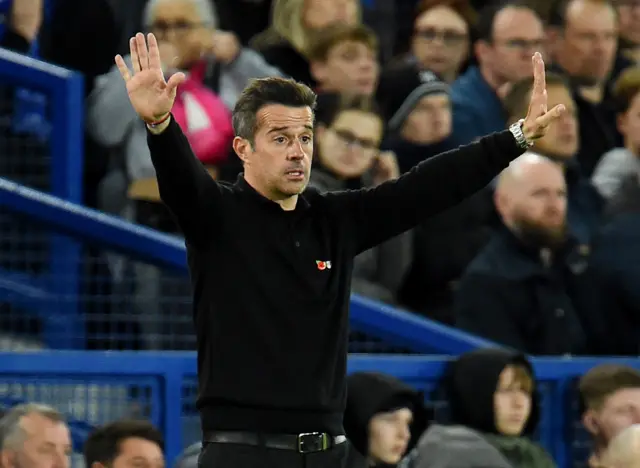 Silva waves his arms in his technical area