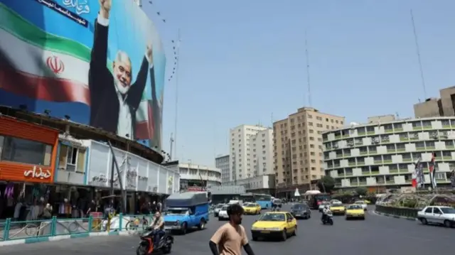 Cars and people on a street in Tehran with a large billboard showing an image of former Hamas leader Ismail Haniyeh (file photo)