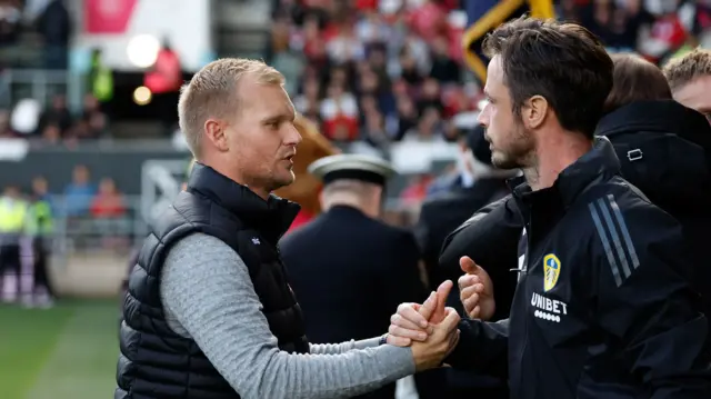 Liam Manning the Bristol City manager shakes hands with the Leeds United coaching staff as he returns to the dugout for the first time since the passing of his son Theo