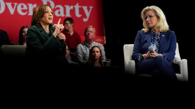 Liz Cheney and Kamala Harris sit on stage during a speech