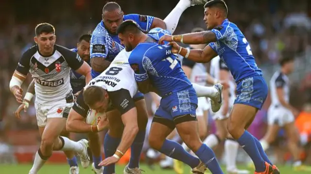 Tom Burgess of England is tackled by Junior Paulo, Royce Hunt and Fa'amanu Brown of Samoa