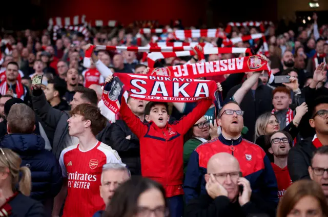 Arsenal fans sing and holds scarves before kick off