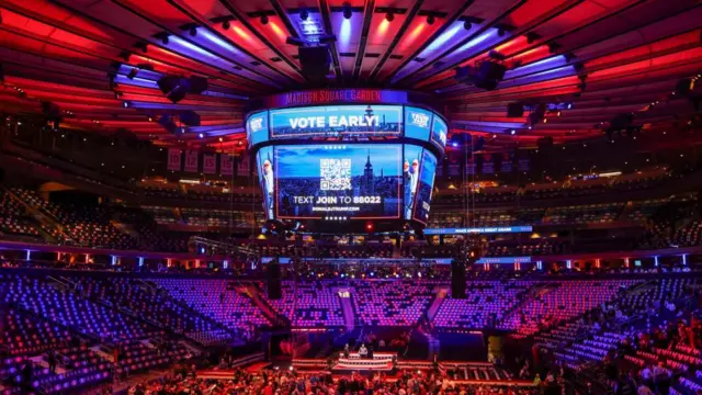 Madison Square Garden lit up in blue and red colours with a big jumbotron that reads: Vote early. There is a picture of Donald Trump on the screen