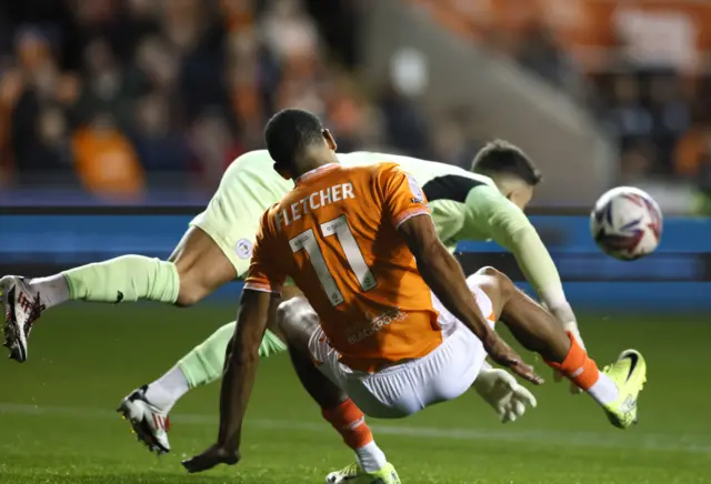 Blackpool's Ashley Fletcher challenges Wigan goalkeeper Sam Tickle.