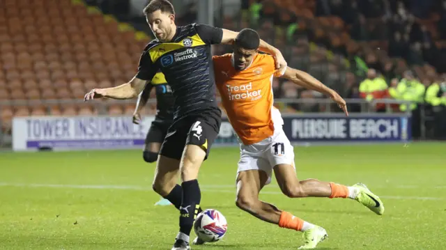 Blackpool's Ashley Fletcher tangles with Wigan's Will Aimson.