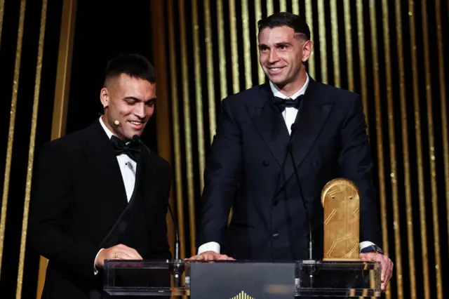 Aston Villa's Argentinian goalkeeper Emiliano Martinez (R) receives the Yashin Trophy for best goalkeeper from Inter Milan's Argentine forward Lautaro Martinez