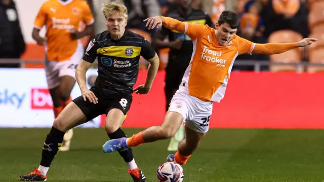 Blackpool's Rob Apter takes a tumble under pressure from Wigan's Matt Smith.