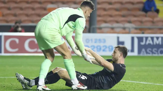 Wigan goalkeeper Sam Tickle lifts up Will Aimson following his own goal