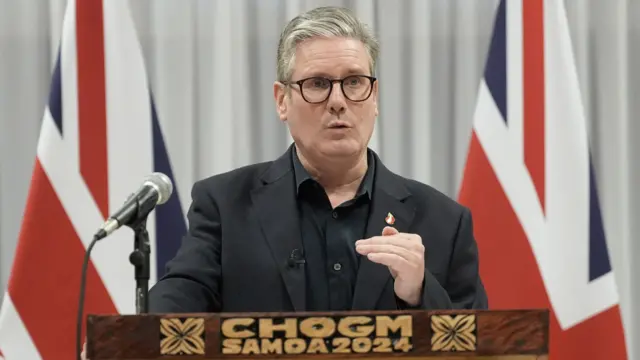 Keir Starmer standing behind a podium in front of two British flags