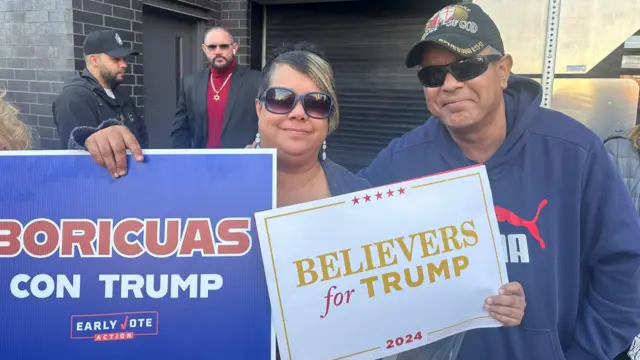 Fermin and Salia holding pro-Trump signs