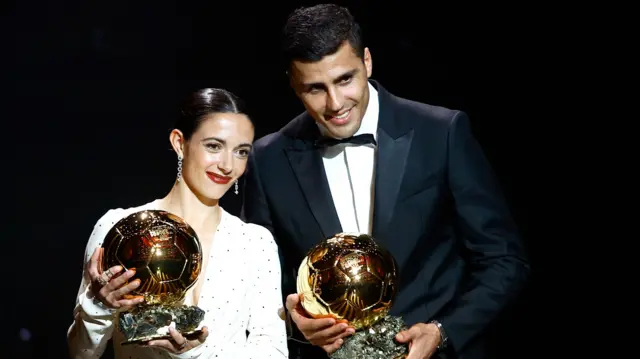 Aitana Bonmati and Rodri holding their Ballon d'Or trophies at the 2024 ceremony