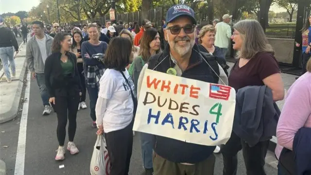 David hangs a sign round his neck reading "white dudes 4 Harris"