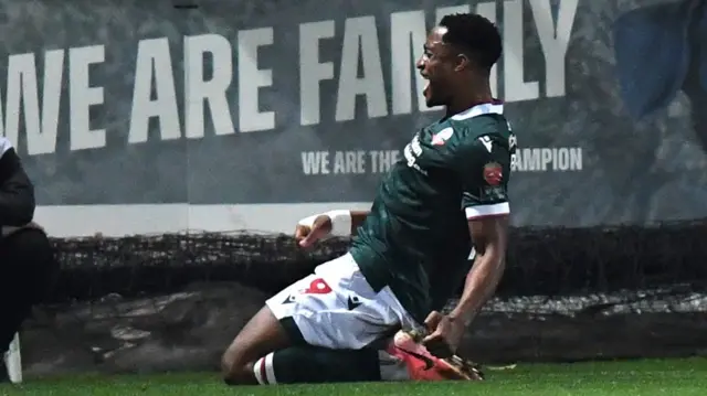 Victory Adeboyejo slides along the turf after scoring Bolton's third at Stevenage