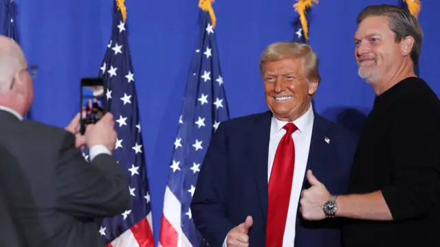 Donald Trump poses for a picture with a man, as another man takes a photo at a campaign event in Pennsylvania