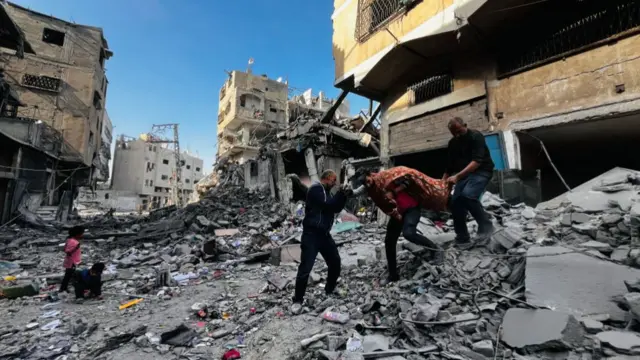 Palestinian first responders remove a body from the rubble of a building hit by an Israeli strike in Beit Lahia, in the northern Gaza Strip