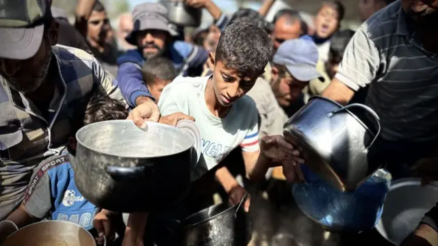 Palestinian children wait in line to receive the food distributed by charitable organizations in Khan Yunis