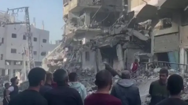 Peope look at rubble at site of strike in Beit Lahia