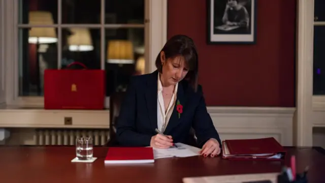 Rachel Reeves sits at a desk writing