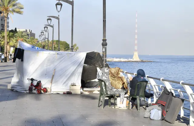 Two women sat on chairs by a makeshift tent in Beirut