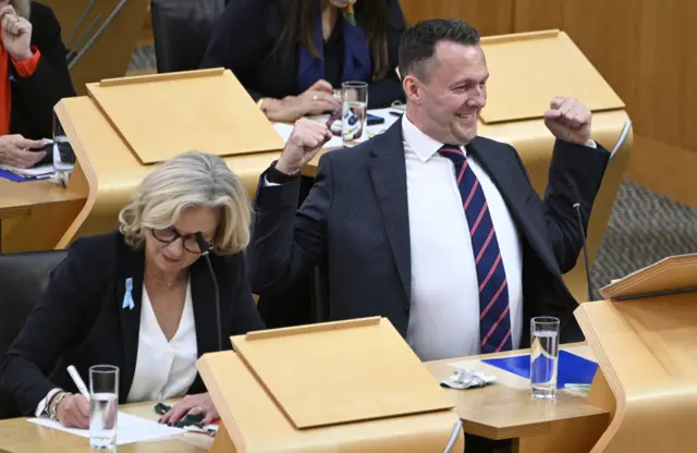 Russell Findlay stretches is arms and shoulders after FMQs