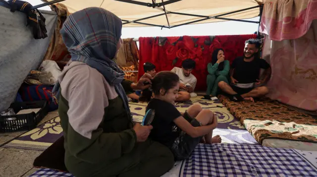 A group of people inside a tent with rugs on the ground