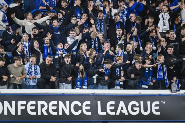 Gent fans with arms out in full voice