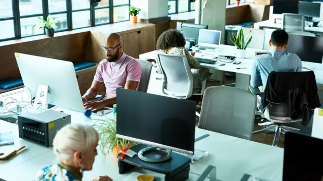 Group of two men and two women using computers and concentrating in modern office environment