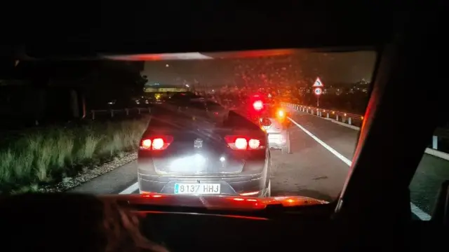 A picture taken at night time looking through the windscreen of a car inside. The view in front is of brake lights of multiple cars ahead