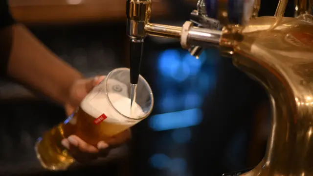 An employee pours a pint of Peroni beer on at the bar in the Mad Hatter pub and hotel, operated by Fuller's, in London on November 30, 2022