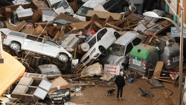 A man inspects a pile of cars and debris that have been washed away by rain in Sedavi, Valencia.