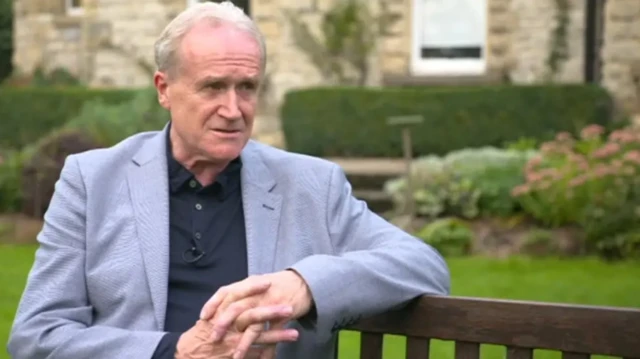 Mike Padgham sits on a garden bench.