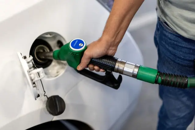 A man fills his car with unleaded fuel at a gas station.