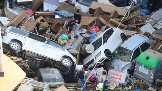 People climb on piled up cars following floods in Sedavi, south of Valencia