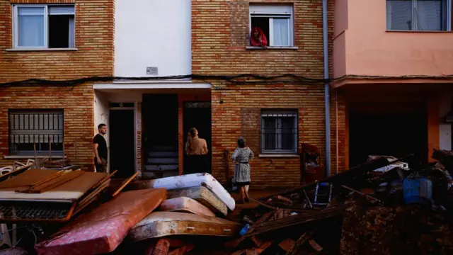 Residents stand outside their homes next to damaged belongings after floods in Utiel, Spain