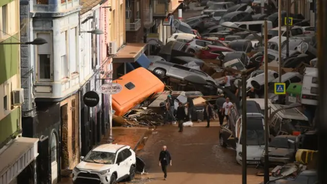 Cars are piled in the street with other debris after flash floods hit Valencia