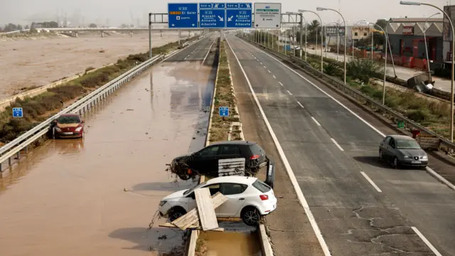 Cars hanging over the side of a ride, near floodwater, in Valencia