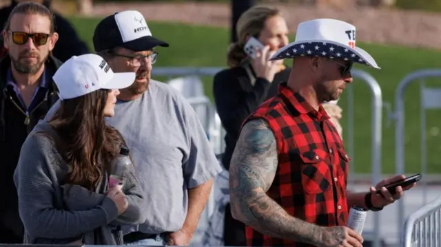 A close up shot of people in line wearing Trump merch