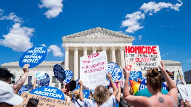 Antiabortion and abortion rights advocates gather outside of the Supreme Court holding various signs