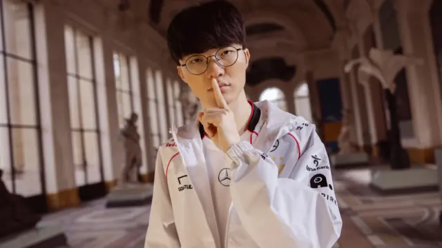 Faker, in his white T1 sports uniform, places his index finger over his lips