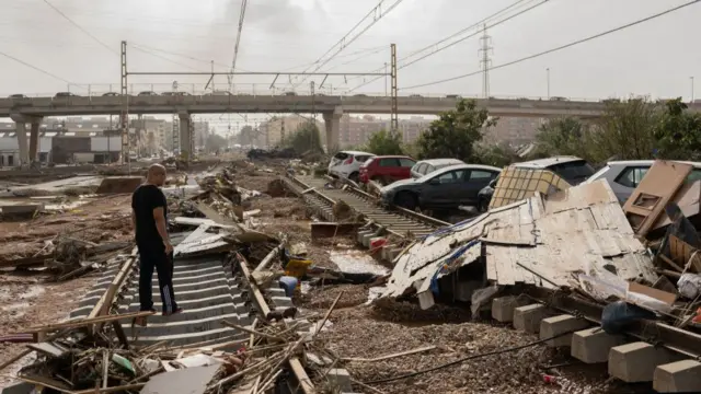 A man walks through a debris-covered railway after flash floods hit the region on October 30, 2024 in the Sedaví area of Valencia, Spain