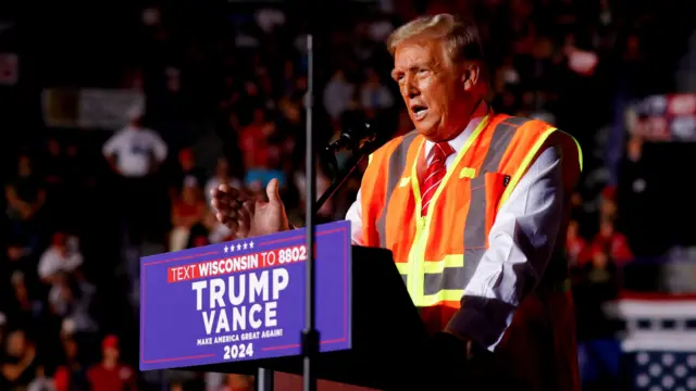 Donald Trump in a safety vest speaks at a rally