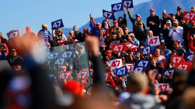 A sea of people holding up signs that have the number 47 on them. The signs are either blue, red or white