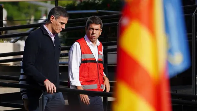 Spanish PM and the president of the Valencian Government walking past a Spanish flag