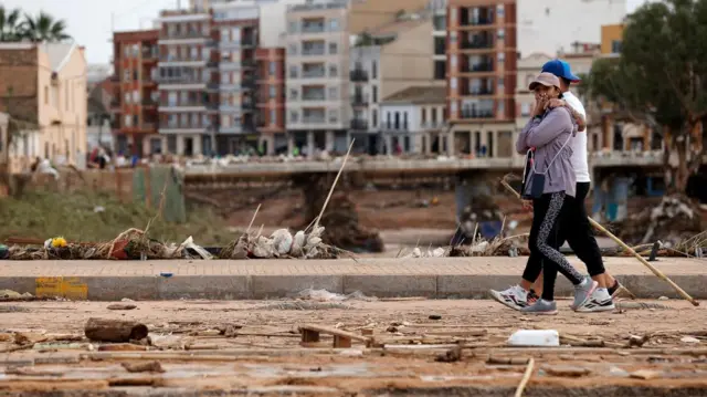 People walk on a mud-covered road in the flood-hit municipality of Paiporta, in the province of Valencia, Spain, 31 October 2024.