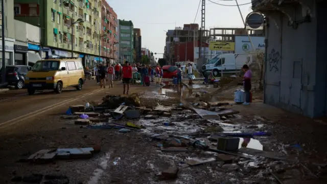 A muddy road with residents in the background