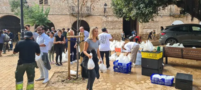 Woman carrying bag of supplies, and other people in the background